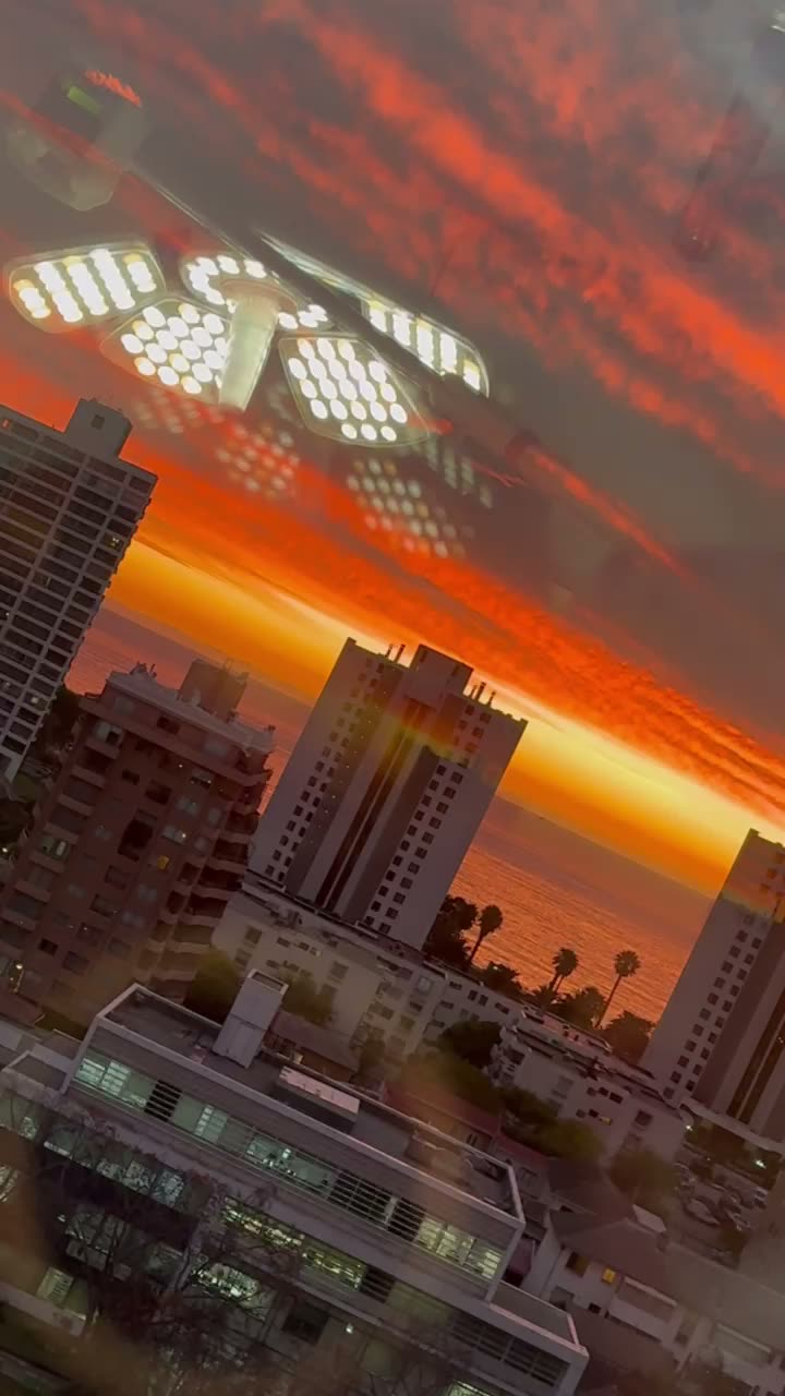 Lámpara del pabellón de Quiromédica reflejada en el ventanal, con el atardecer de Viña del Mar
